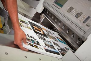 printing press operator moving brochures in production