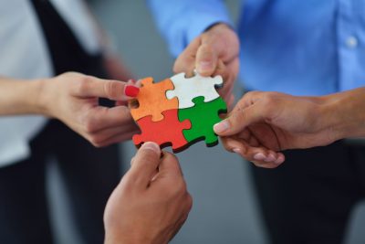 four business people joining puzzle pieces of different colors